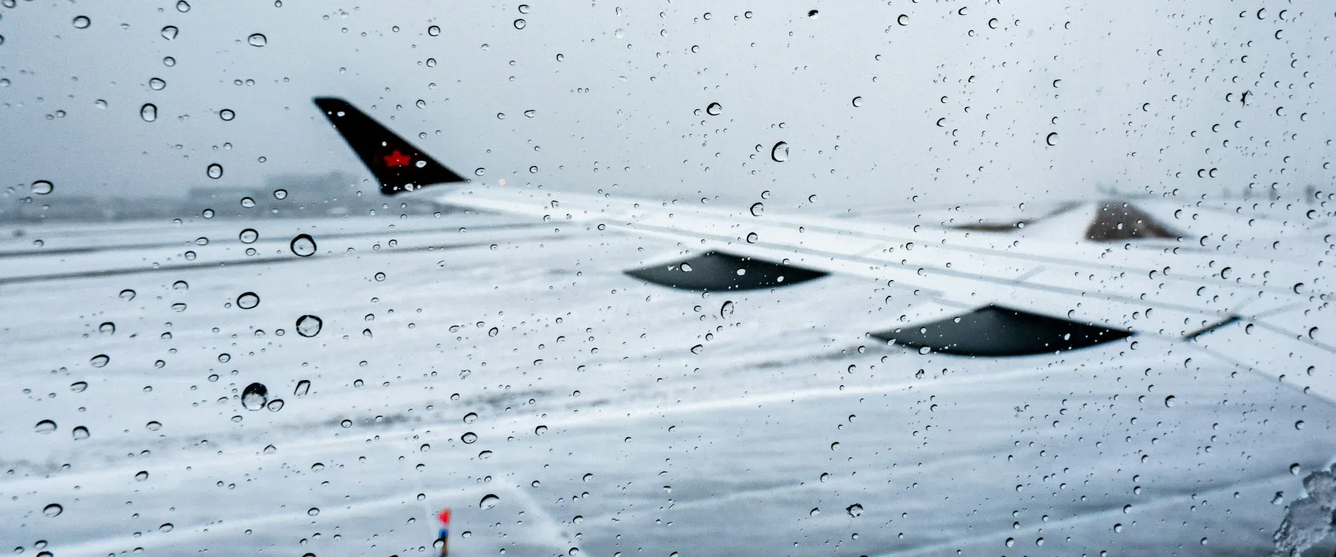 View of an airplane wing through a rainy window