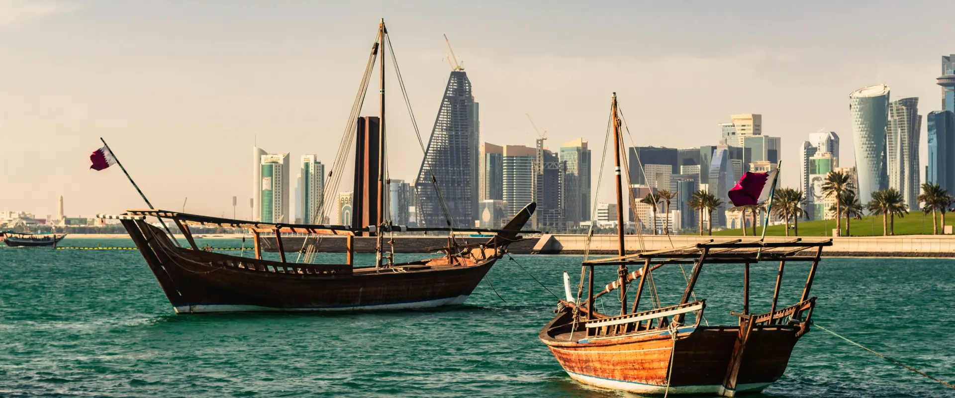 Boats float on the water with the Doha skyline behind them