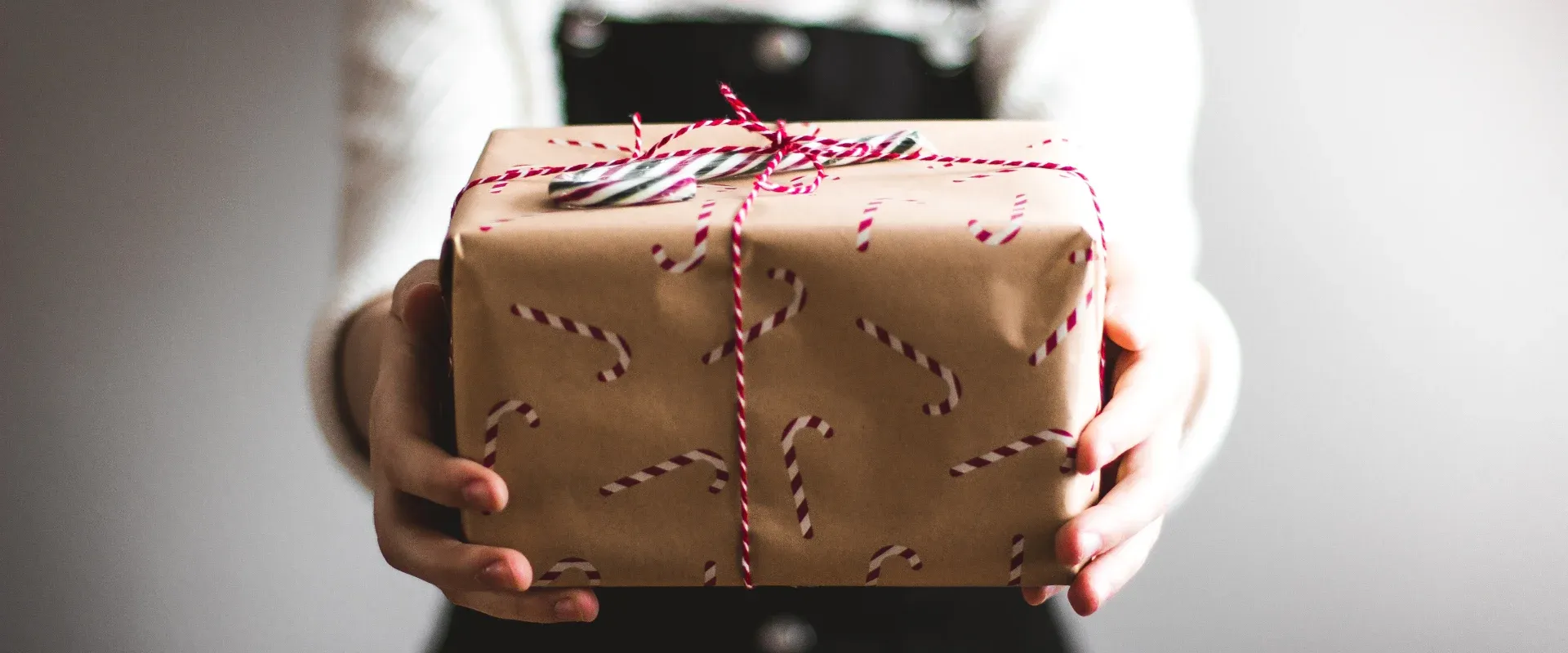 Person holds a gift covered in candy cane wrapping paper