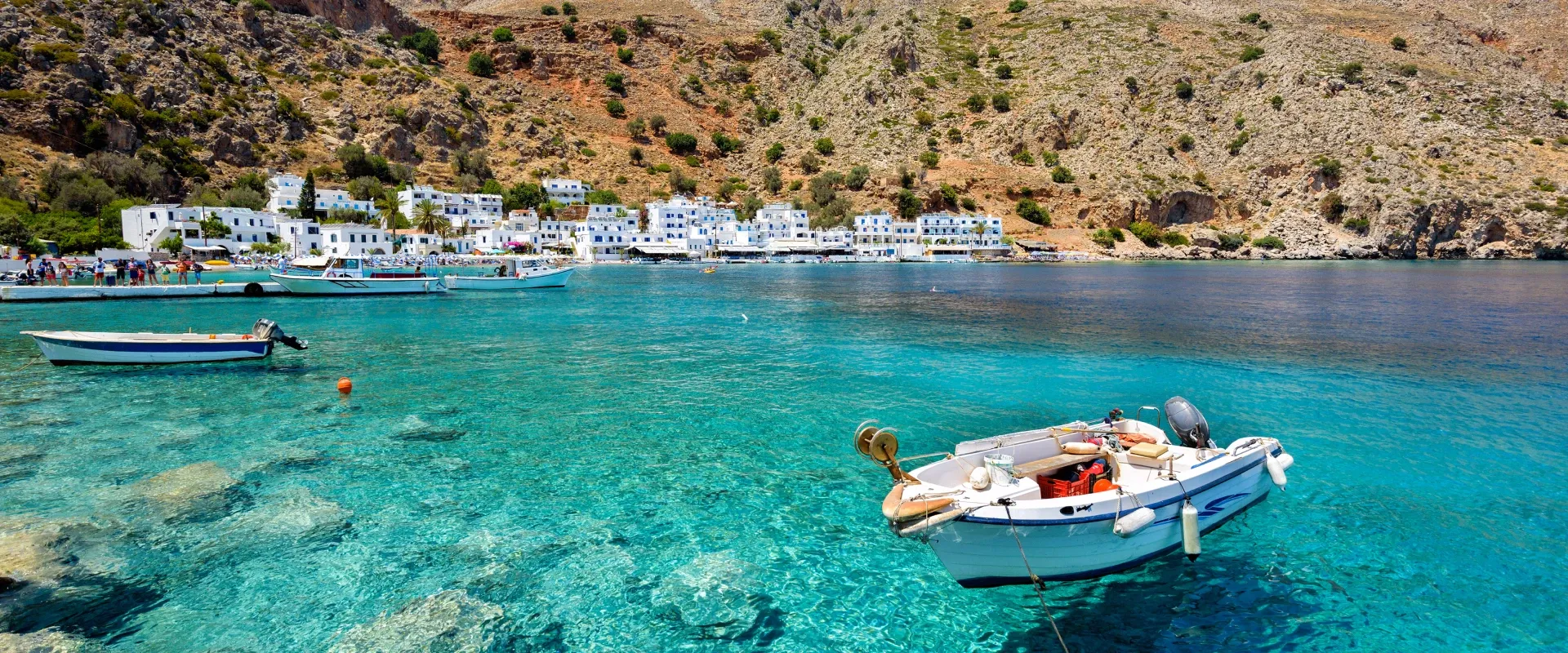 A boat floats in the turquoise blue water off the coast of Crete
